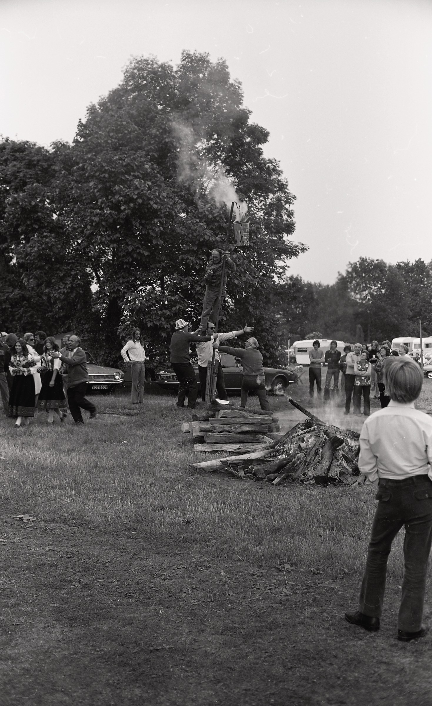 Jāņu svinēšana LNPL Latviešu mājā Almelijā, Herefordšīrā, 1973. gada 30. jūnijā. No kreisās tautas tērpos Daina Vanags un Indra Sinka, Jānis Velde, vīrietis starp automašīnām Jānis Ūdris. Sieviete ar puķainu blūzi Valija Indruše ar vīru. Labajā malā Maija Bisenieks.