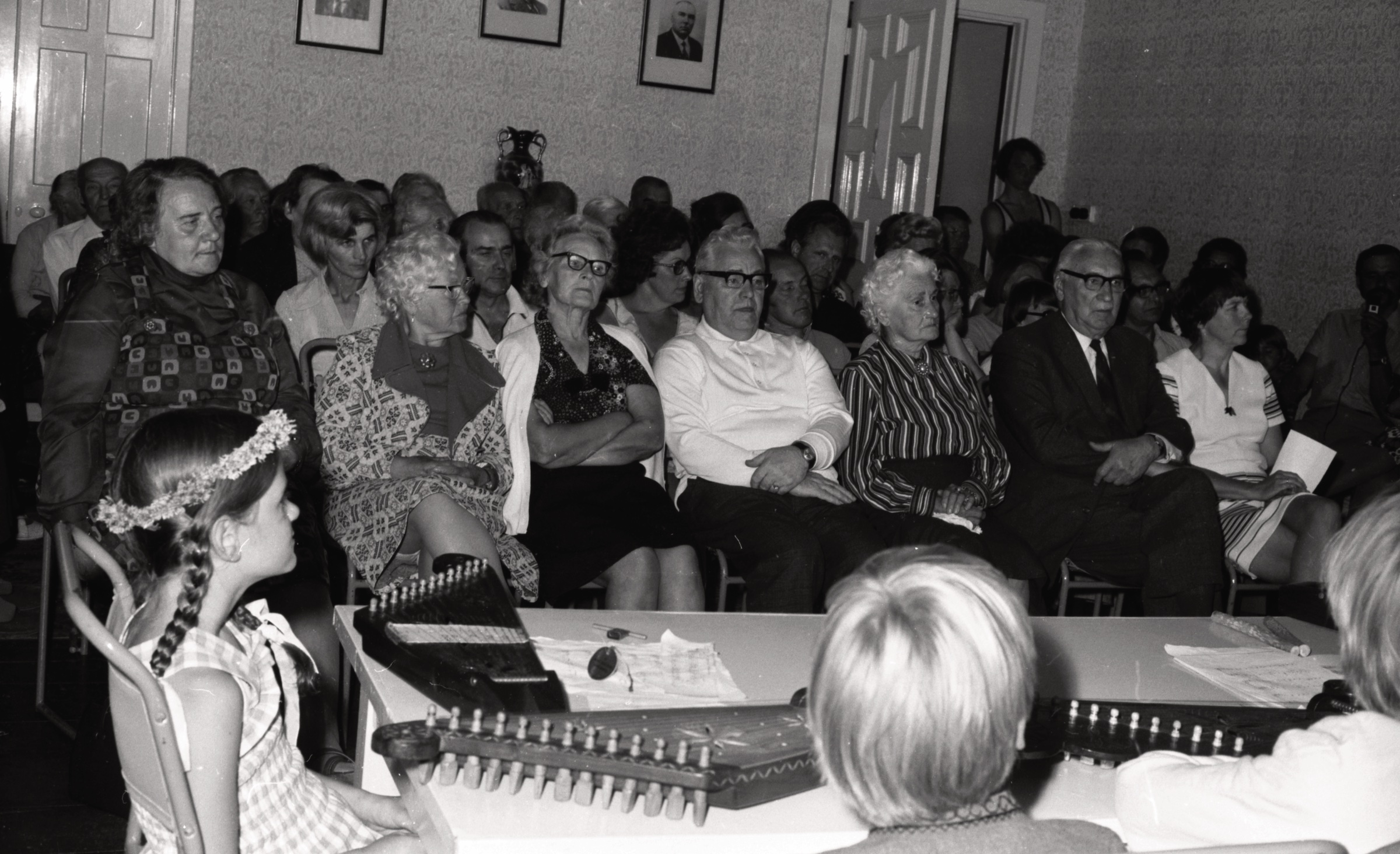 Bērnu nometnes uzstāšanās LNPL Latviešu mājas iedzīvotājiem Almelijā, Herefordšīrā, 1974. gads. Meitene ar vainadziņu - Amanda Bonner. Skatītāju pirmā rinda 1. no kr. Pētersona k-dze, 4. Rūdolfs Priede, 6. Jānis Skujevics, 2. rindā no kr. Ārija un Jānis Silinski.