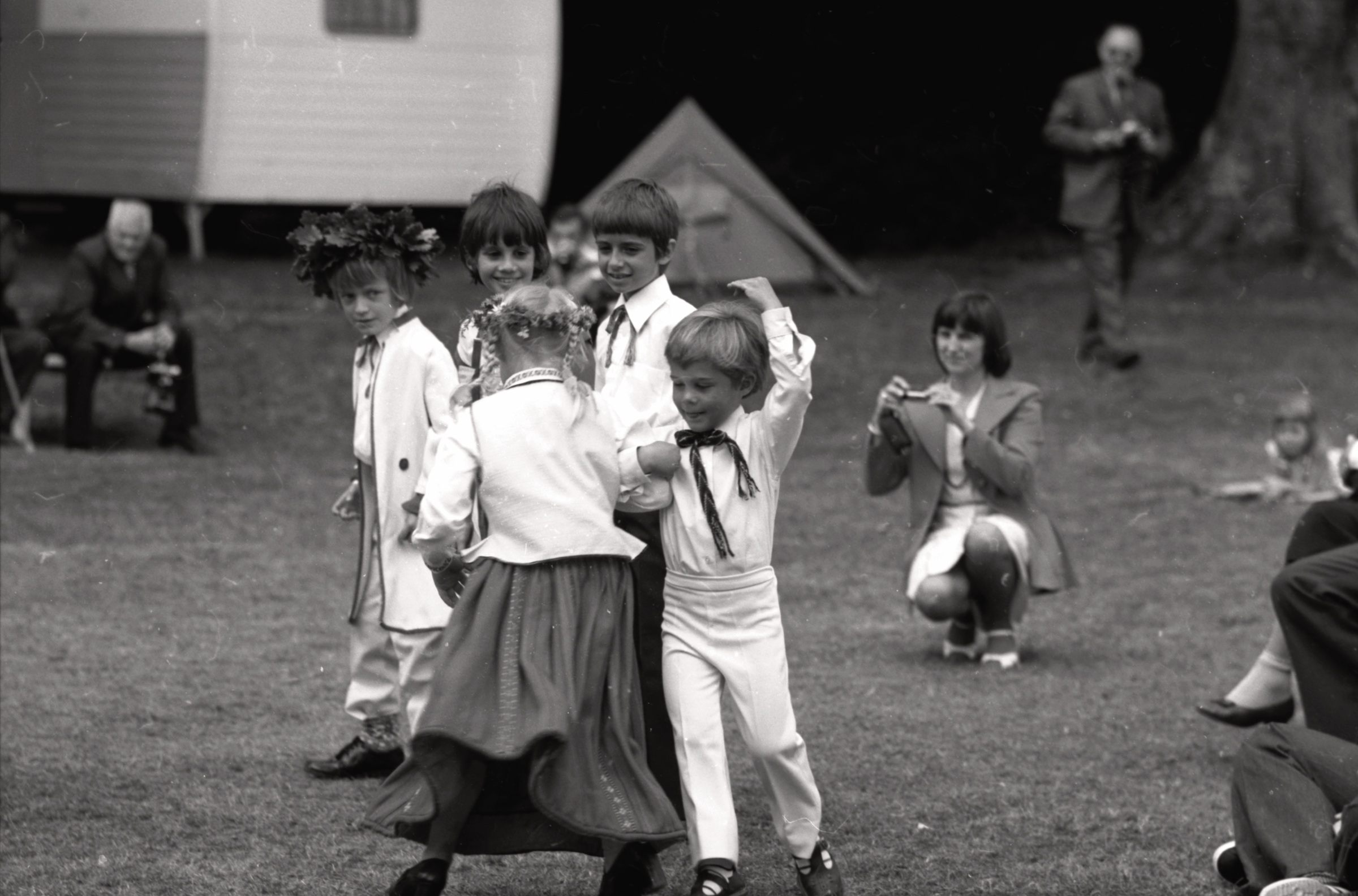 Priekšnesums jauno latviešu dejotāju izpildījumā LNPL Latviešu mājā Almelijā, Herefordšīrā, 1978. gads. No kr. ar vainagu Pauls Muravskis, nezināms, Daunis Auers, Tamāra Dempsey, Andrejs Pipistrelli, notupusies fotografē Astrīda Ligere.