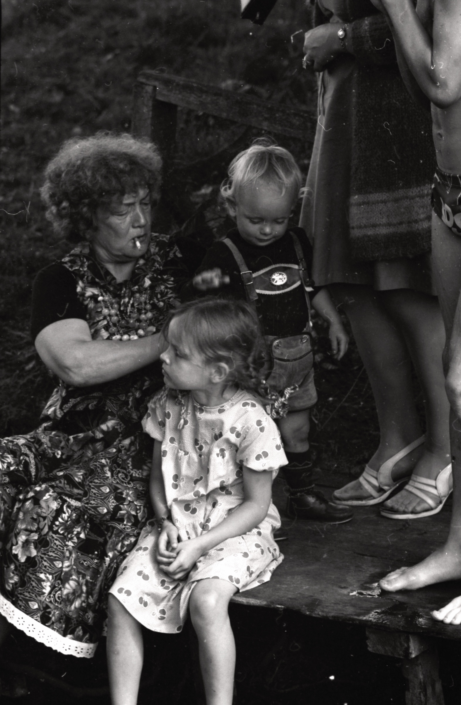 Austra Korps ar mazbērniem Māri un Līviju Uskaļiem 1978. gada vasarā uz ezera laipas LNPL Latviešu mājā Almelijā, Herefordšīrā.