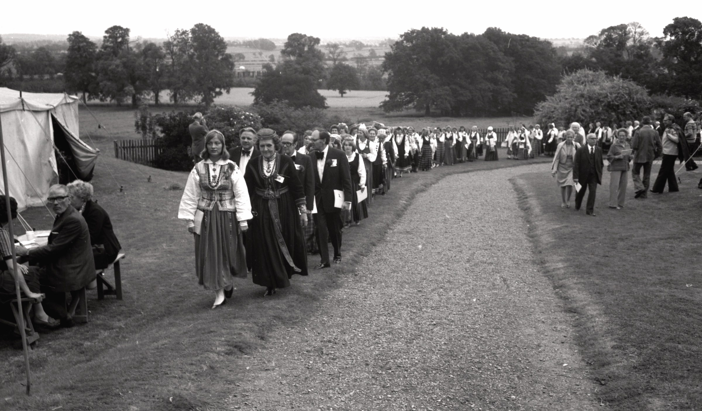 Dalībnieku gājiens 2. Anglijas latviešu brīvdabas dziesmu dienās DVF lauku īpašums 'Straumēni', Catthorpe Manor, Lesteršīra, 1978. gada 3. septembris. Gājiena priekšā no kr. Lilija Zobens un Ērika Sarkanbārdis, otrā rindā no kr. Juris Jurģis, Ziedonis Āboliņš, Manzars Dreimanis.